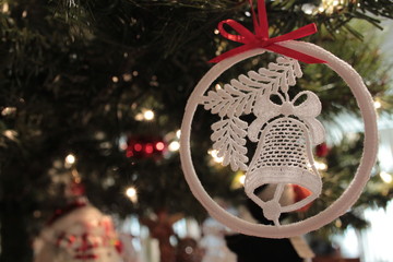 Close up of lace bell Christmas ornament hanging from red ribbon on Christmas tree