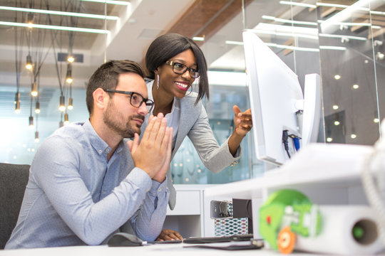 Business Colleagues Praying For Success While Looking At Project On Computer's Monitor In Office.