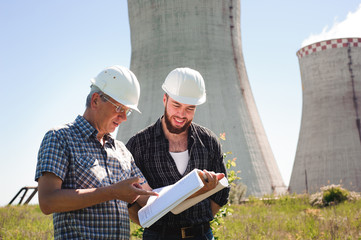 Male architects reviewing documents together at electric power plant