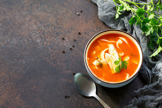 Tomato soup with pasta and chicken in a bowl on a dark stone background. The concept of healthy eating. Copy space.