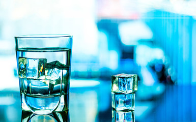 Glass of Water with ice cubes on blue Background
