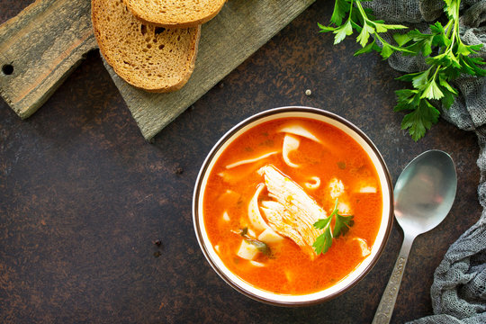 Tomato soup with pasta and chicken in a bowl on a dark stone background. The concept of healthy eating. Top view with copy space.