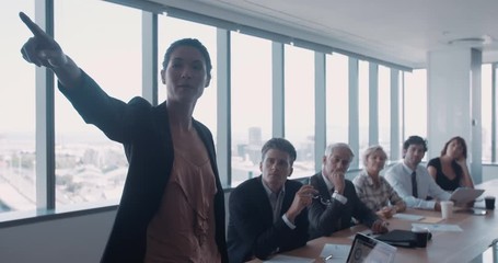 Female executive giving presentation to colleagues in meeting room at office. Businesswoman explaining new business ideas to coworkes in conference room. - Powered by Adobe