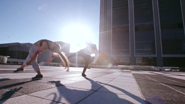 Young man and woman practicing parkour in the city. Urban runners in action doing flips outdoors.