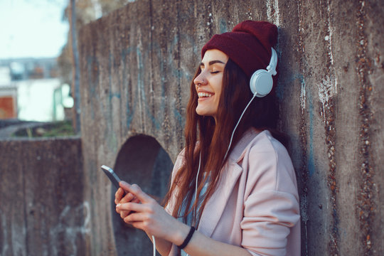 Young urban woman listens to music via headphones and smartphones