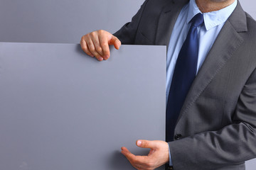 Businessman holding a blank board, standing near blank