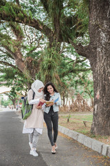 two asian student walking on campus