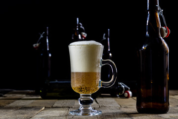 A pint of tasty beer on a wooden table. Beer in pint and beer bottles.