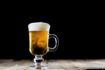 A pint of tasty beer on a wooden table. Beer in pint and beer bottles.
