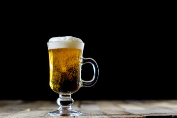 A pint of tasty beer on a wooden table. Beer in pint and beer bottles.