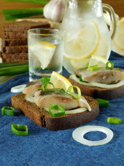 Salted herring with onion and lemon on a slice of bread and misted glass vessels