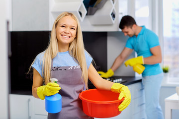 Young family couple doing cleaning in the kitchen.
