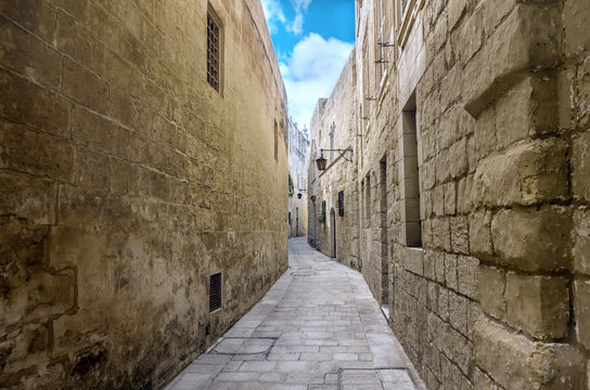 Fototapeta beautiful view of ancient bleak narrow medieval street in town Mdina, Malta, toned style