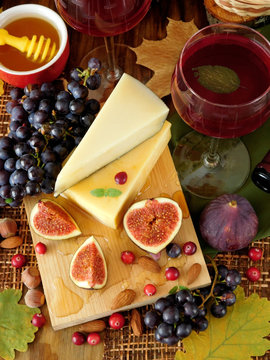 Parmesan on a board surrounded by figs, grapes, cranberries and honey