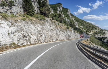 Fototapeta premium Country road through the rocky mountains and forest.