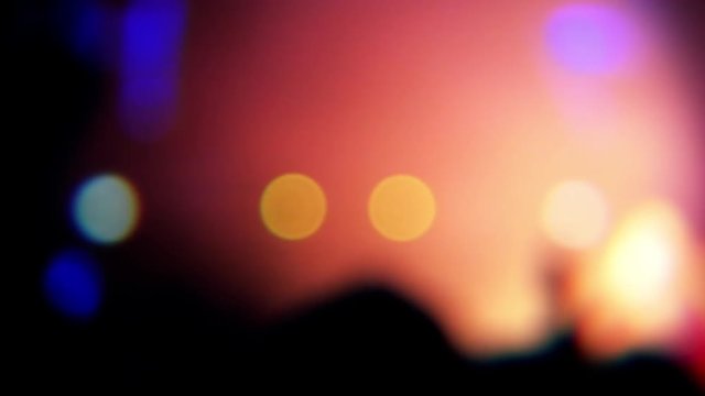 Blurred people clapping hands at music concert. Vibrant and colorful light show.