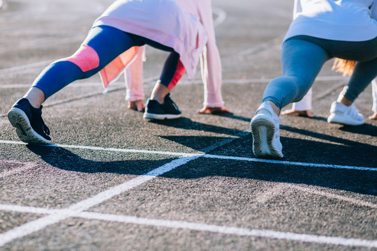 Sport, Healthy Life And Millenialls Concept. Back View Of Female Runners In Start Position On Stadium. Toned