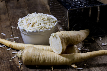Root of parsley root on grater. Grate and parsley on the old kitchen table in the kitchen.
