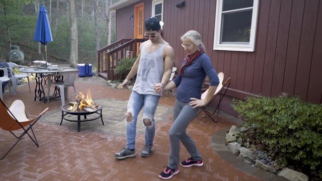 Mother and son holding hands do a joyous dabke dance with harms raised with a fire burning nearby.