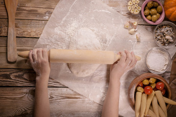Children's hands knead dough on a wooden table. Baking preparing background.