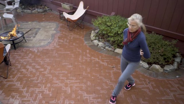 Mature blonde woman practices middle eastern folk dance on her patio.