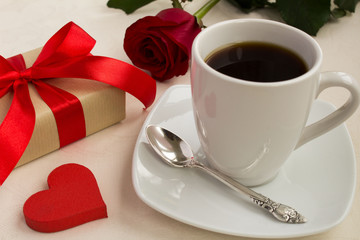Coffee,gift and red rose on the beige tablecloth