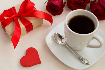 Coffee,gift and red roses on the beige tablecloth.View from above.