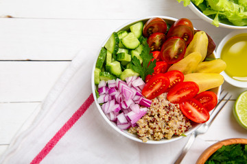 Vegetarian Buddha salad bowl with red onions mixed cheery tomatoes, cucumbers and quinoa with an oil and lime on the side. Top horizontal view copy space.

