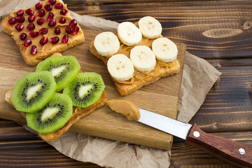 Toasts  with peanut paste and fruit on the wooden cutting board