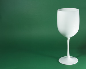 A glass of white wine on a green background. 