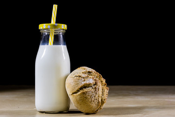 Ingredients, for breakfast. Milk in a bottle and bread on a kitchen table. Wooden kitchen table.