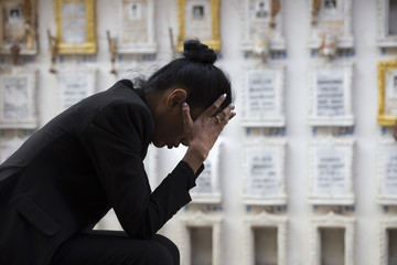 Sad woman sitting near a grave