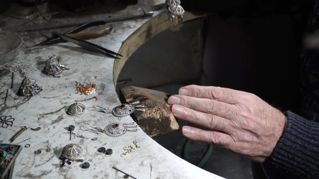 Video shooting of hands of the jeweler from a close distance. The old jeweler is working on the creation of jewelry