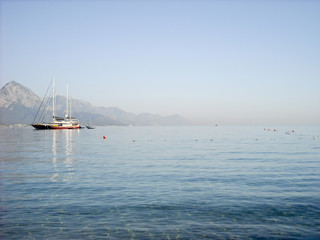Kemer Antalya bella vista sul mare. Spiaggia Kemer Antalya con sabbia e montagne, il mare con la nave. Bellissimo porto vicino alla spiaggia di sabbia.