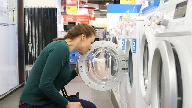 Beautiful woman buying washing machine in supermarket. 