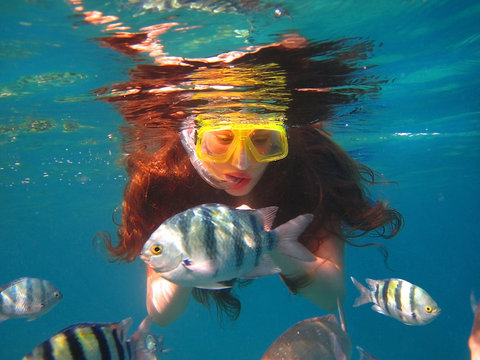 girl among tropical fish in Red Sea, Eilat, Israel