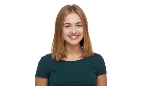 Portrait of beautiful female 20s blowing air kiss on camera being flirty and candid expressing her romantic feelings over white background. Concept of emotions
