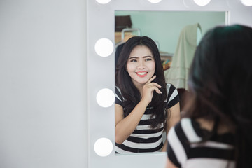 woman looking at her skin in the mirror