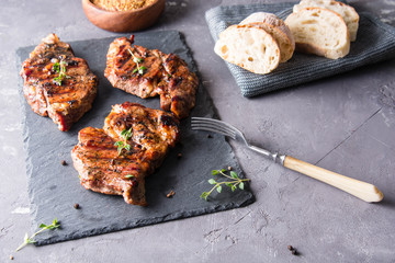 Grilled beef steak with fresh baguette,thyme, salt and pepper on black stone plate.