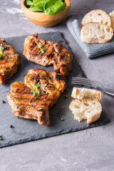 Grilled beef steak with fresh baguette,thyme, salt and pepper on black stone plate.