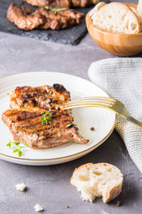Grilled pork steak with thyme on a white plate.
