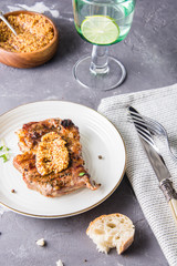 Grilled pork steak with thyme on a white plate.