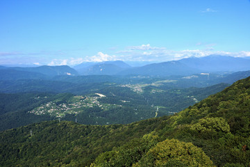 Panorama of the mountains in the area of Krasnaya Polyana/Panorama of Sochi in the Krasnaya Polyana area. There are mountains, clouds, air haze, vegetation. Sochi, Russia, mountain landscape