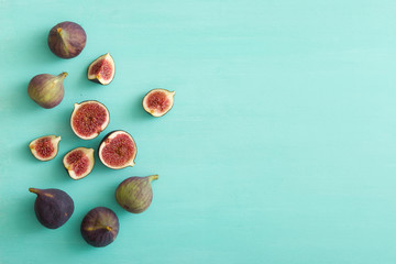 Top view on sliced and full fresh figs on turquoise wooden table or background. Healthy snack and food.