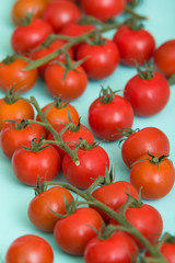 Closeup on fresh organic cherry tomatoes on turquoise wooden background.