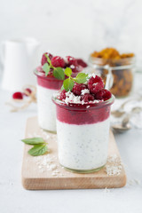 Layered raspberry smoothies with chia seeds, fresh raspberry and coconut on a light stone background. Useful dessert. Selective focus.