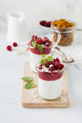 Layered raspberry smoothies with chia seeds, fresh raspberry and coconut on a light stone background. Useful dessert. Selective focus.