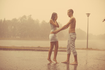 Loving couple in the rain barefoot. A man and a woman in love.