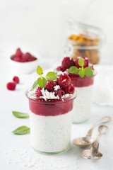 Layered raspberry smoothies with chia seeds, fresh raspberry and coconut on a light stone background. Useful dessert. Selective focus.
