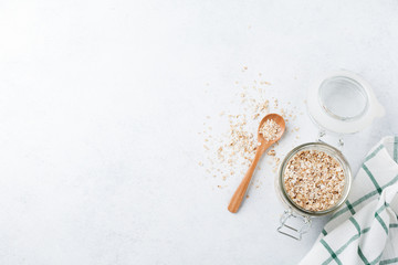Raw oat flakes in a glass jar on a light background.Oatmeal. Selective focus.Top view. Copy space.
